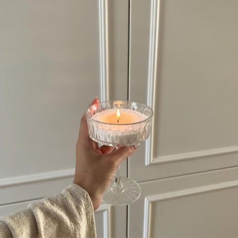 3. Woman holding a lit Candledust powder candle in a glass, highlighting reusable extra wicks