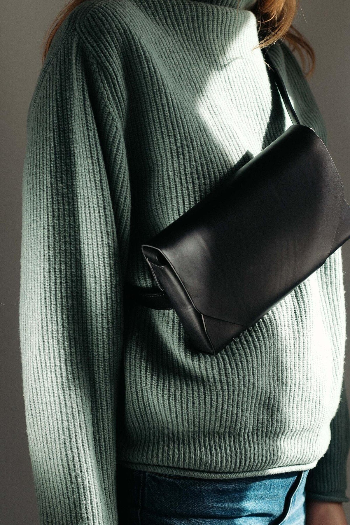 10. Woman wearing black leather Stella Soomlais bumbag over green ribbed sweater in natural light