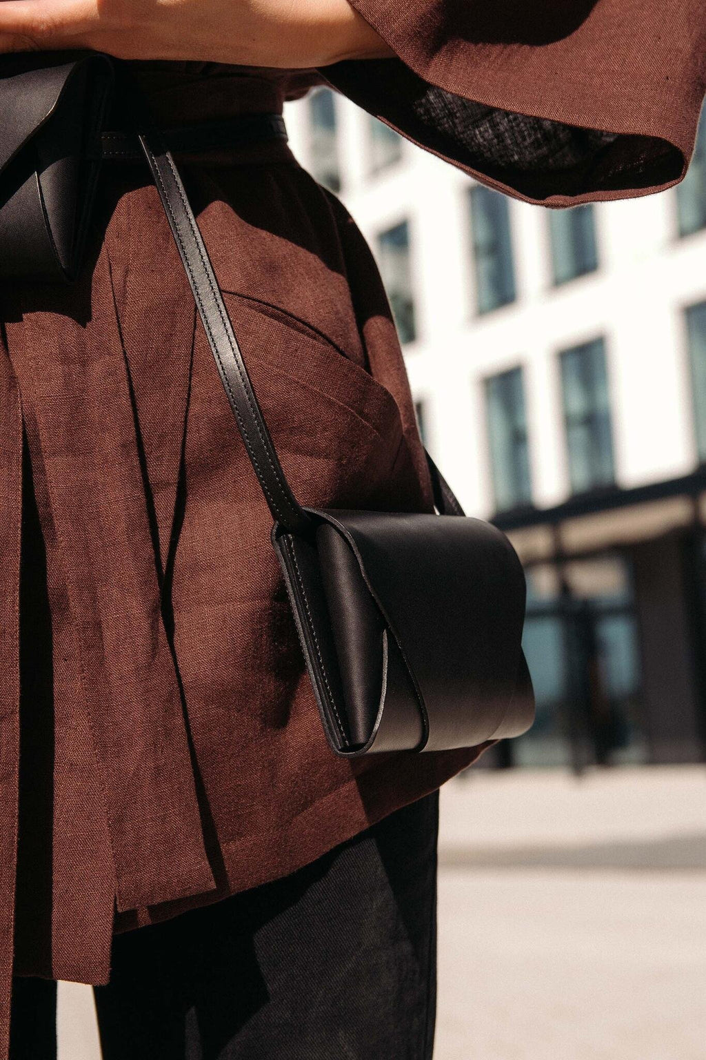 3. Woman wearing black leather Stella Soomlais Capital of Plenty clutch-wallet crossbody in urban setting