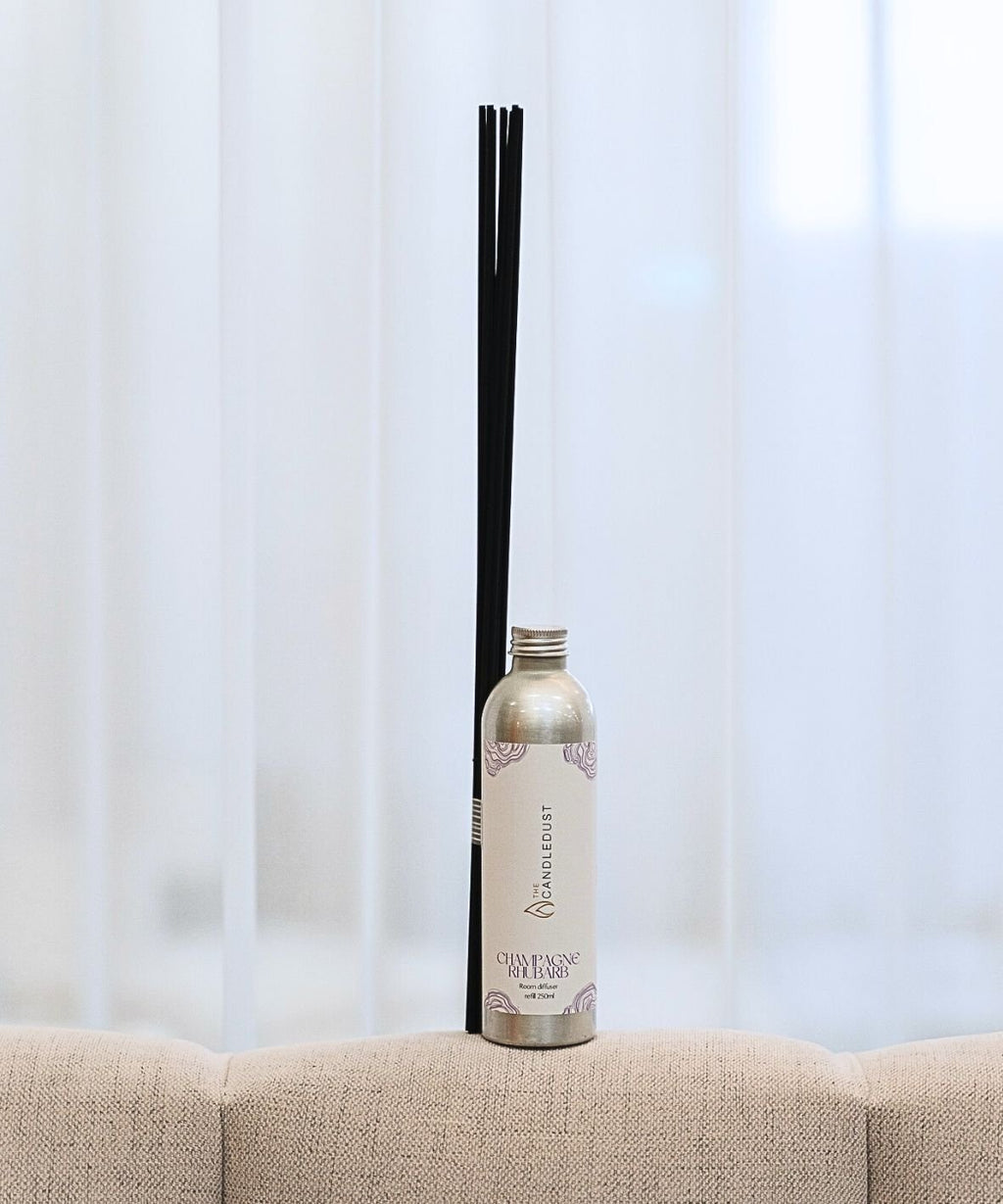 1. Candledust Champagne Rhubarb room diffuser refill with black sticks on a beige sofa