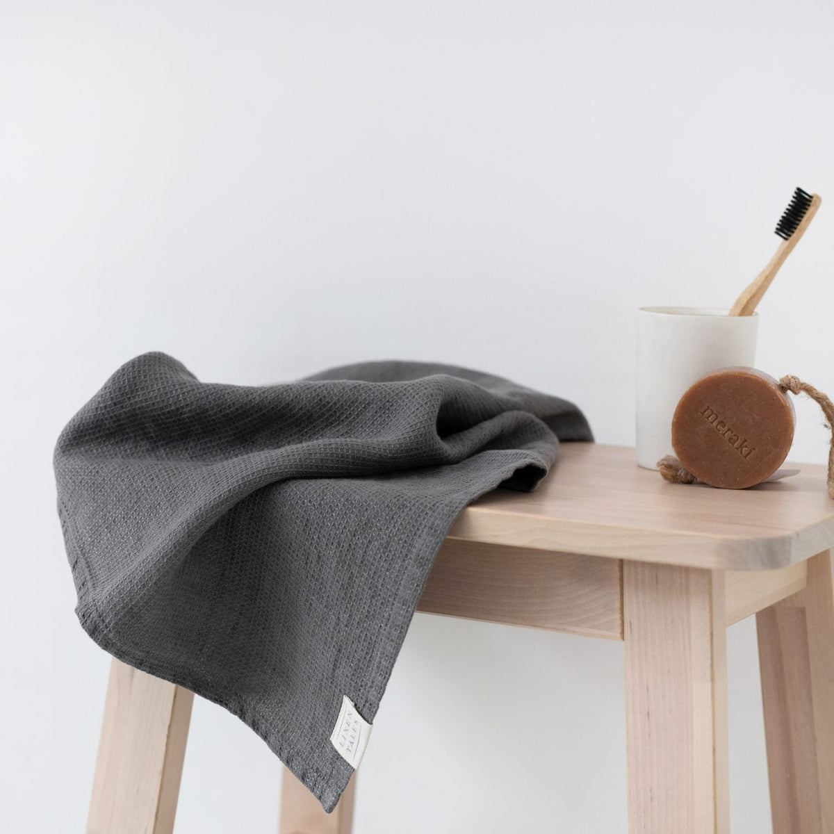 4. Charcoal waffle linen towel on a wooden stool with a toothbrush and soap, clean bathroom aesthetic