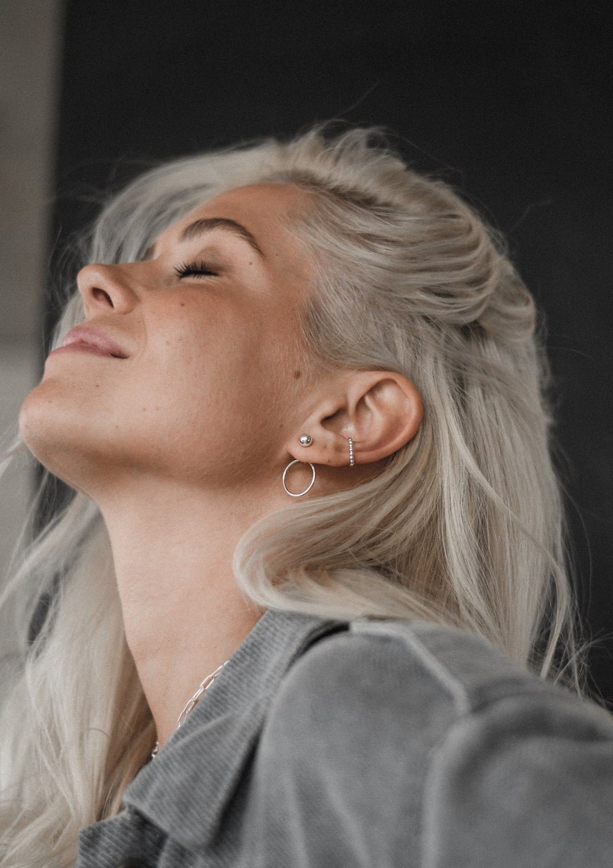 3. Woman smiling while wearing NO MORE Chord Earrings in silver, highlighting elegant design in lifestyle setting