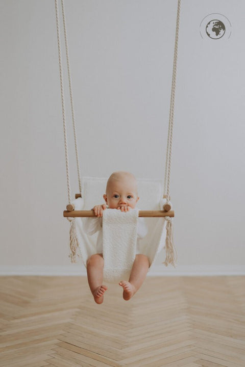 3. Baby in bouclé snow white swing with oak wood poles, facing forward in a bright room