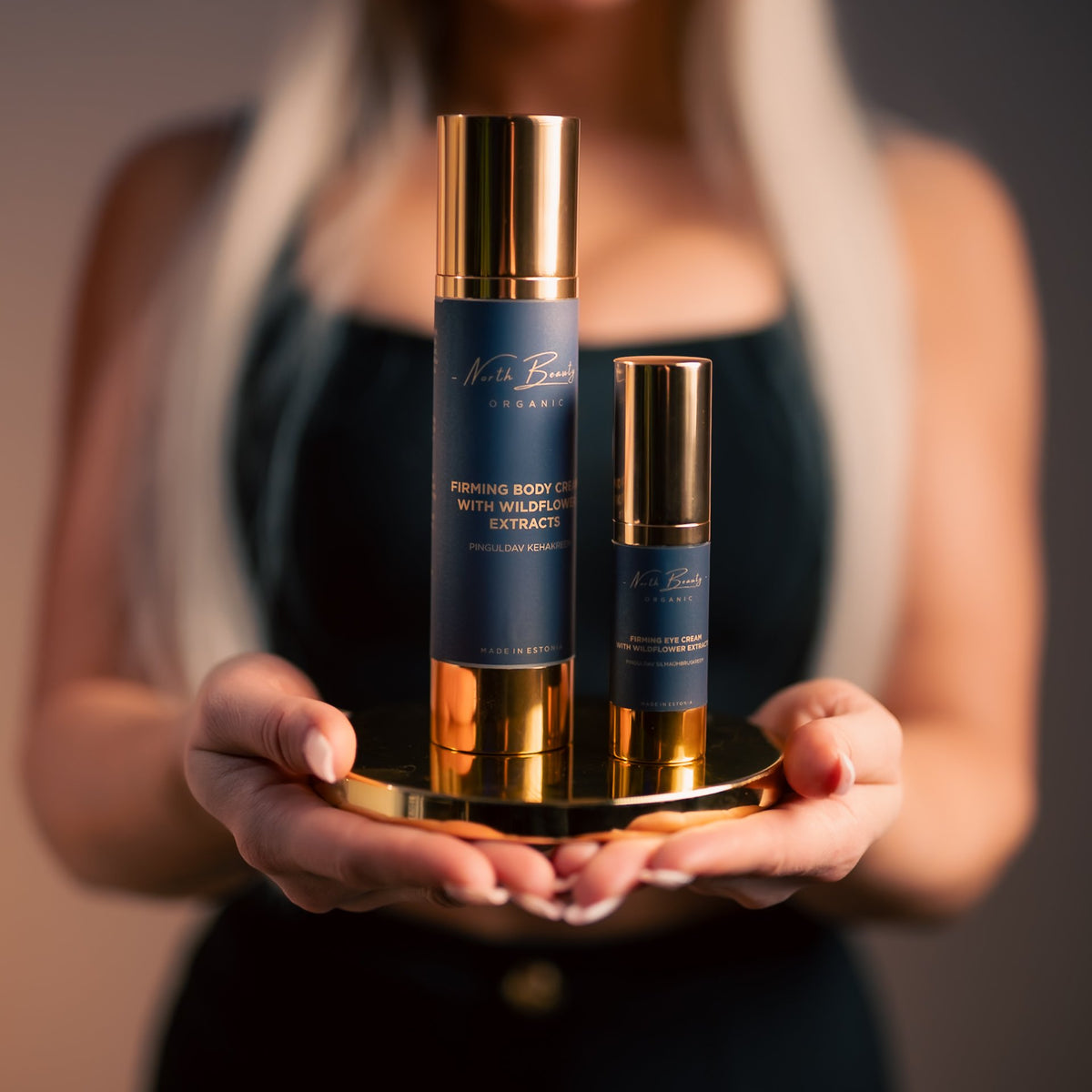 2. North Beauty Firming Body Cream and smaller bottle on a gold tray, held by a woman, highlighting elegant design