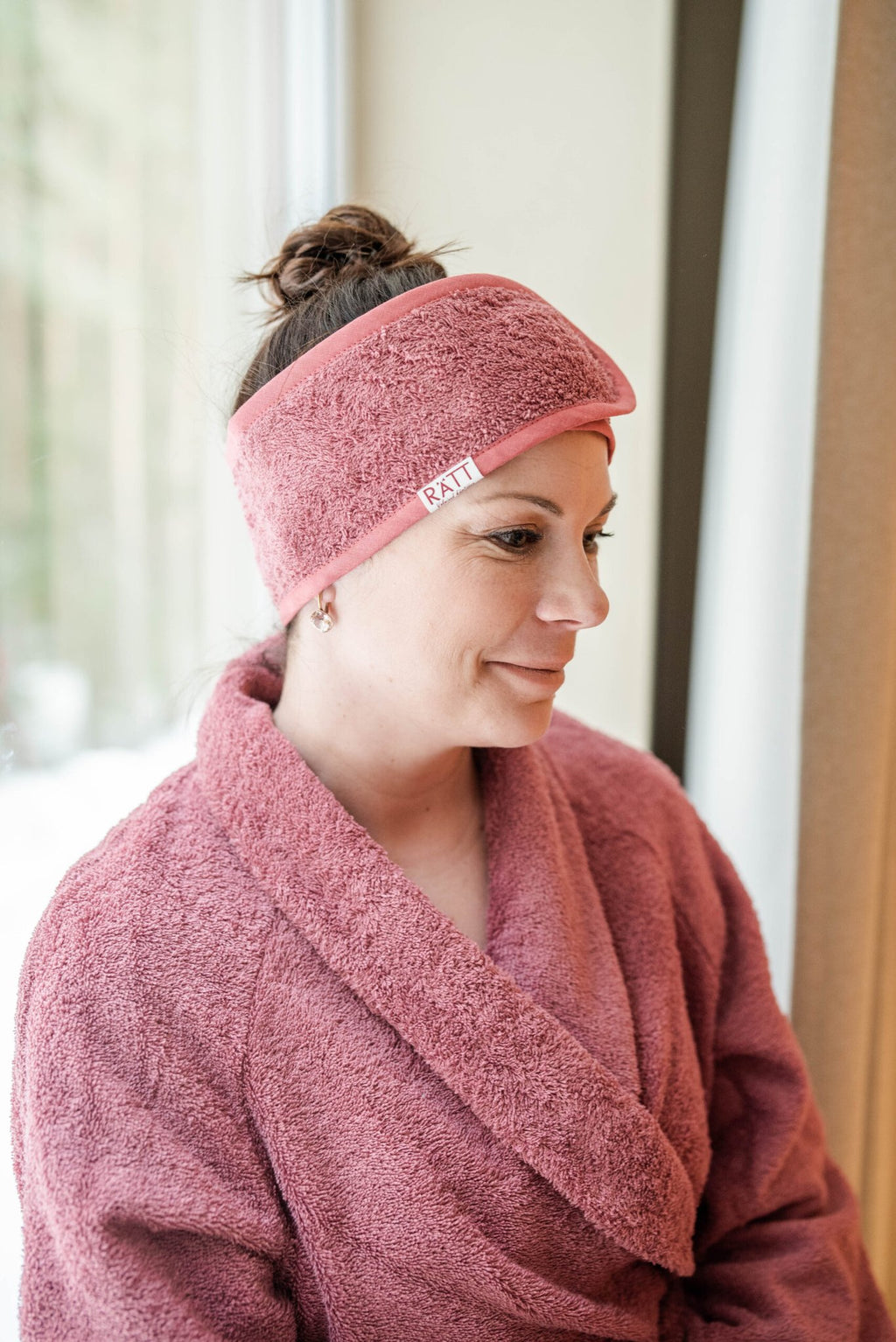 3. Woman in pink robe wearing RÄTT cotton terry headband, emphasizing comfort and style