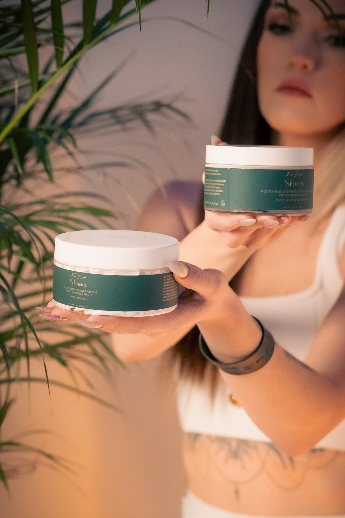 1. Woman holding North Beauty Nourishing Shower Cream with Amber Extract, creating a spa-like ambiance