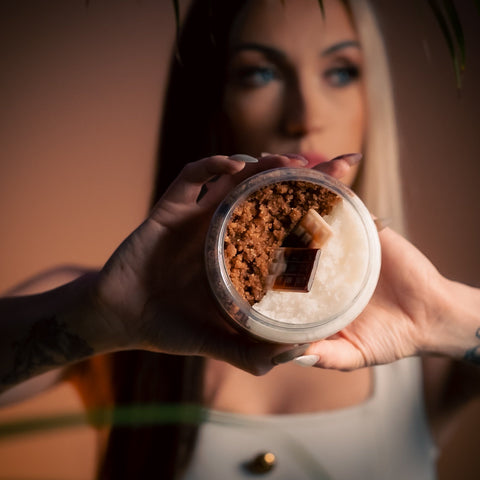 1. Woman holding North Beauty Chocolate and Vanilla Body Scrub, showcasing texture and chocolate pieces