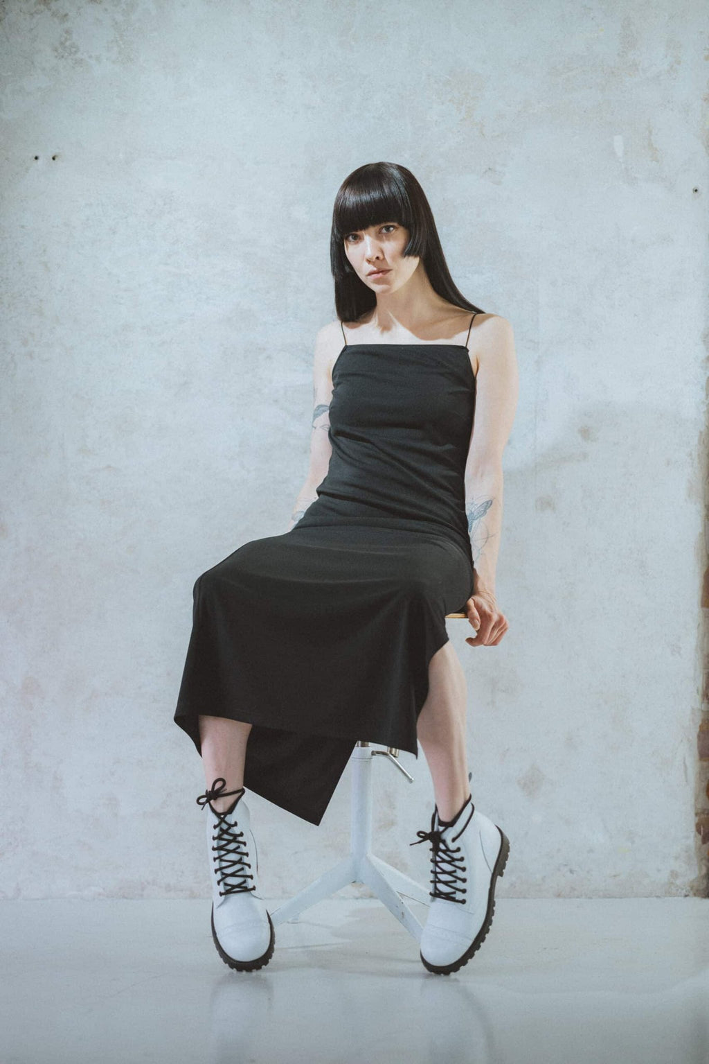 2. Woman crouching in Samelin 517 Aviator Boots in white, paired with a black dress, highlighting versatile style