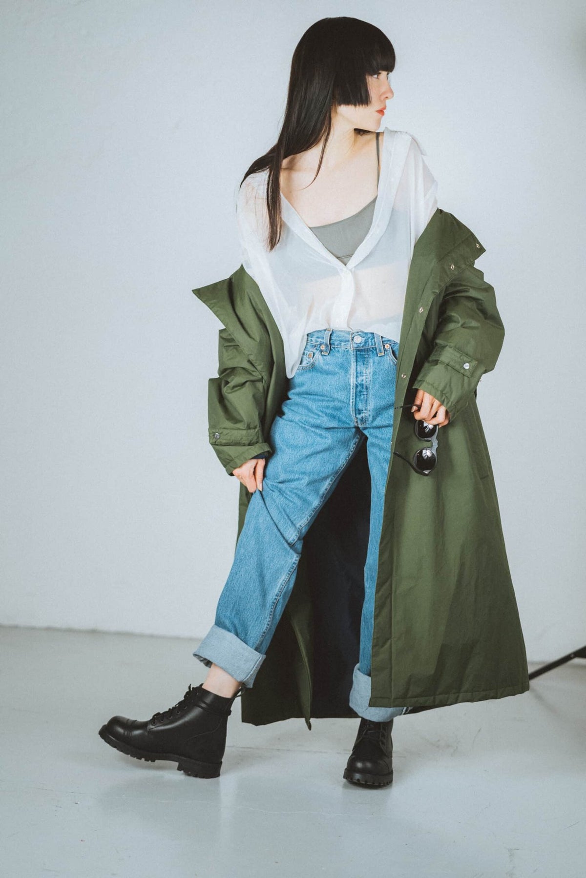 2. Woman posing in Samelin 517 Aviator Boots, black, with green coat and jeans, holding a drink