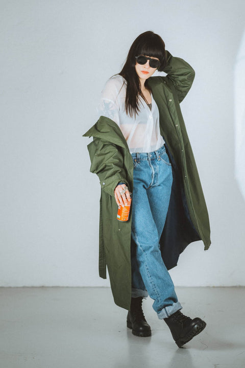 1. Woman wearing Samelin 517 Aviator Boots in black, tying laces, styled with green coat and jeans