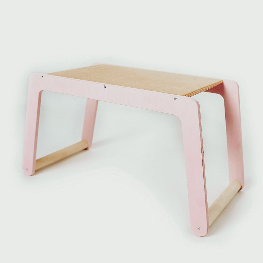 2. Children's small desk with pink legs and natural wood top in studio setting