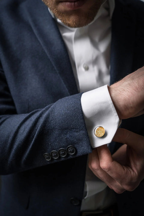 1. Man wearing dark suit with white shirt, showcasing Eherüs yellow trout leather cufflinks