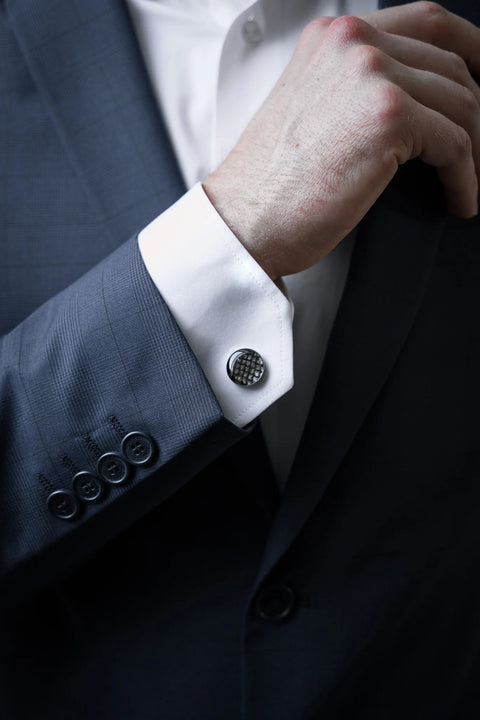 1. Man wearing dark suit with white shirt showcasing Eherüs round cufflinks made from brown trout leather
