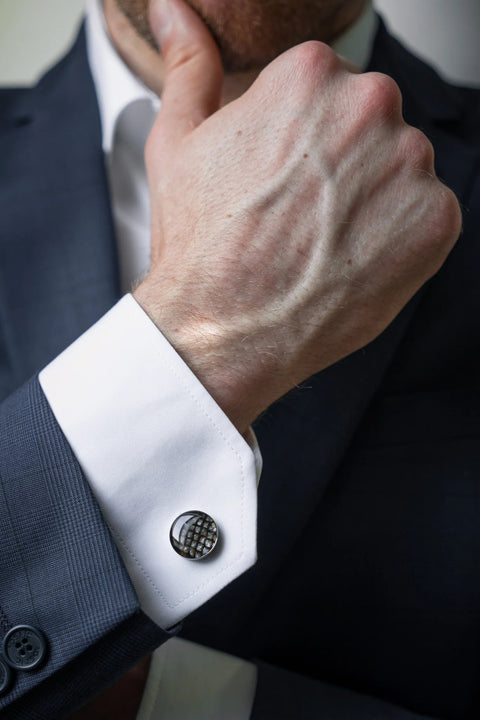 2. Close-up of man in dark suit with hand on chin, highlighting Eherüs round cufflinks in brown trout leather