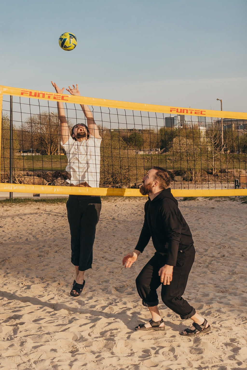 4. Two men playing beach volleyball wearing Omaking Lauri Leather Sandals in brown, demonstrating sporty functionality