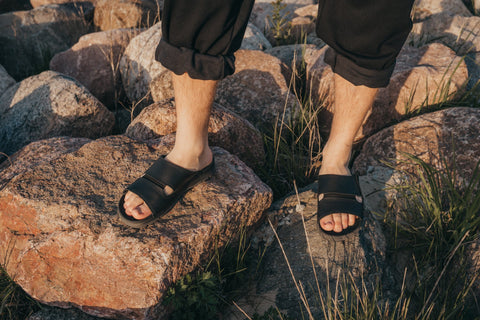 3. Men's black Miku sandals by Omaking shown on rocks in an outdoor setting