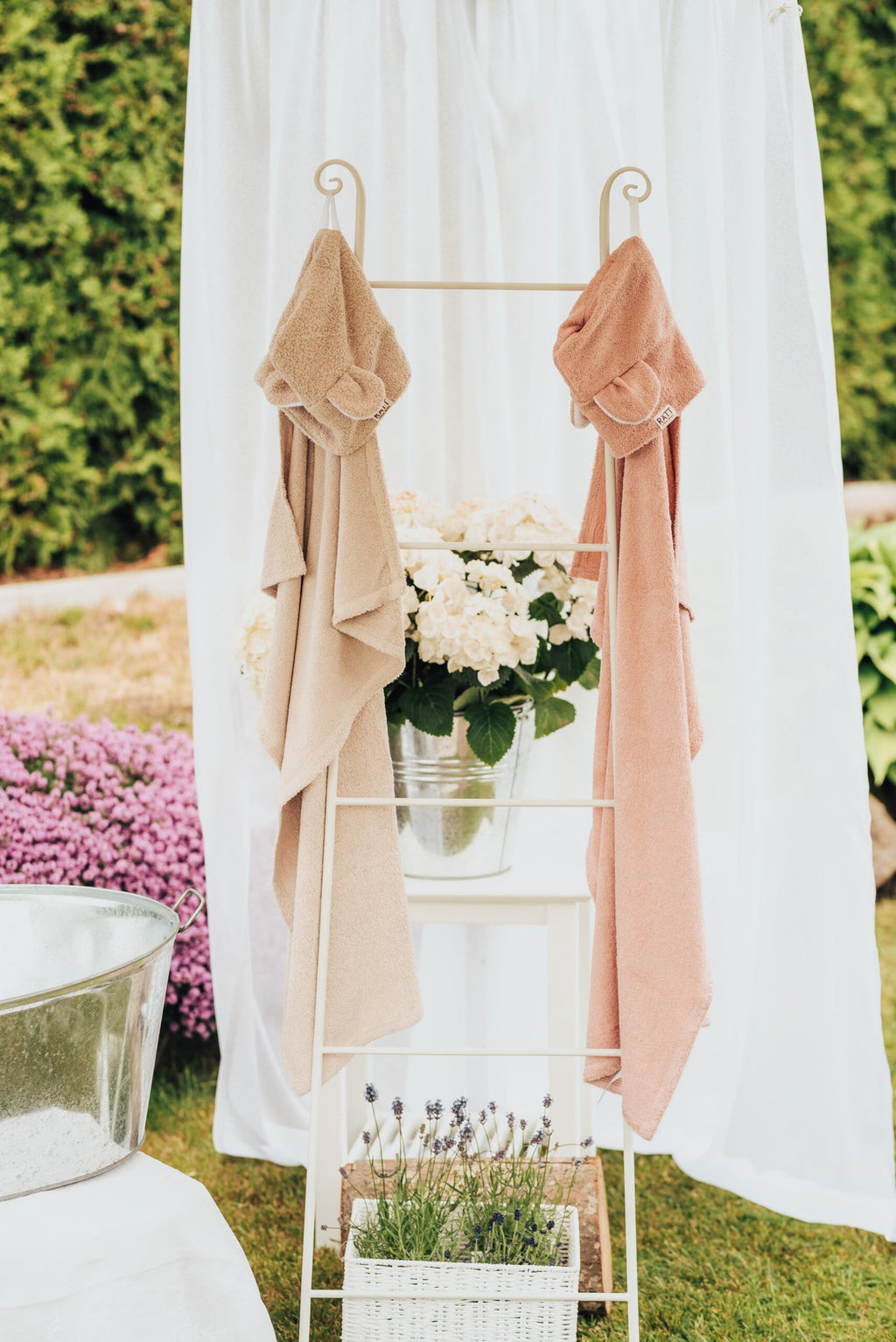 4. RÄTT Hooded Baby Bath Towels TEDDY in beige and pink displayed on rack with flowers, outdoor setting