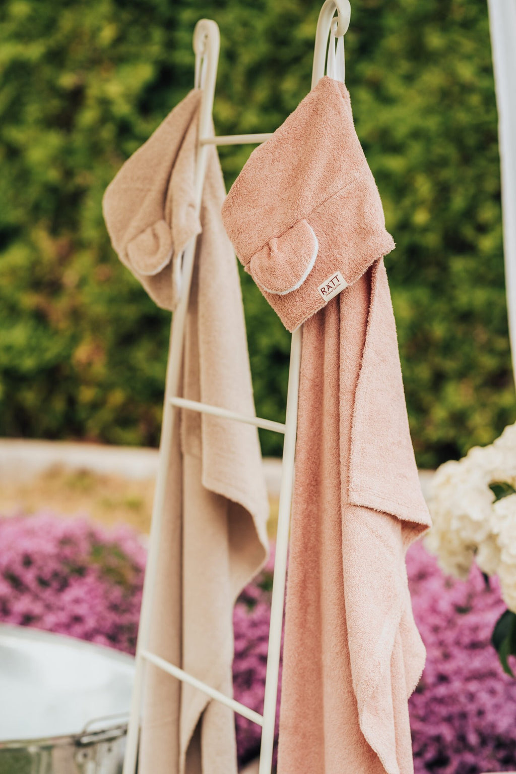 3. RÄTT Hooded Baby Bath Towels TEDDY in beige and pink hanging on rack, outdoor setting