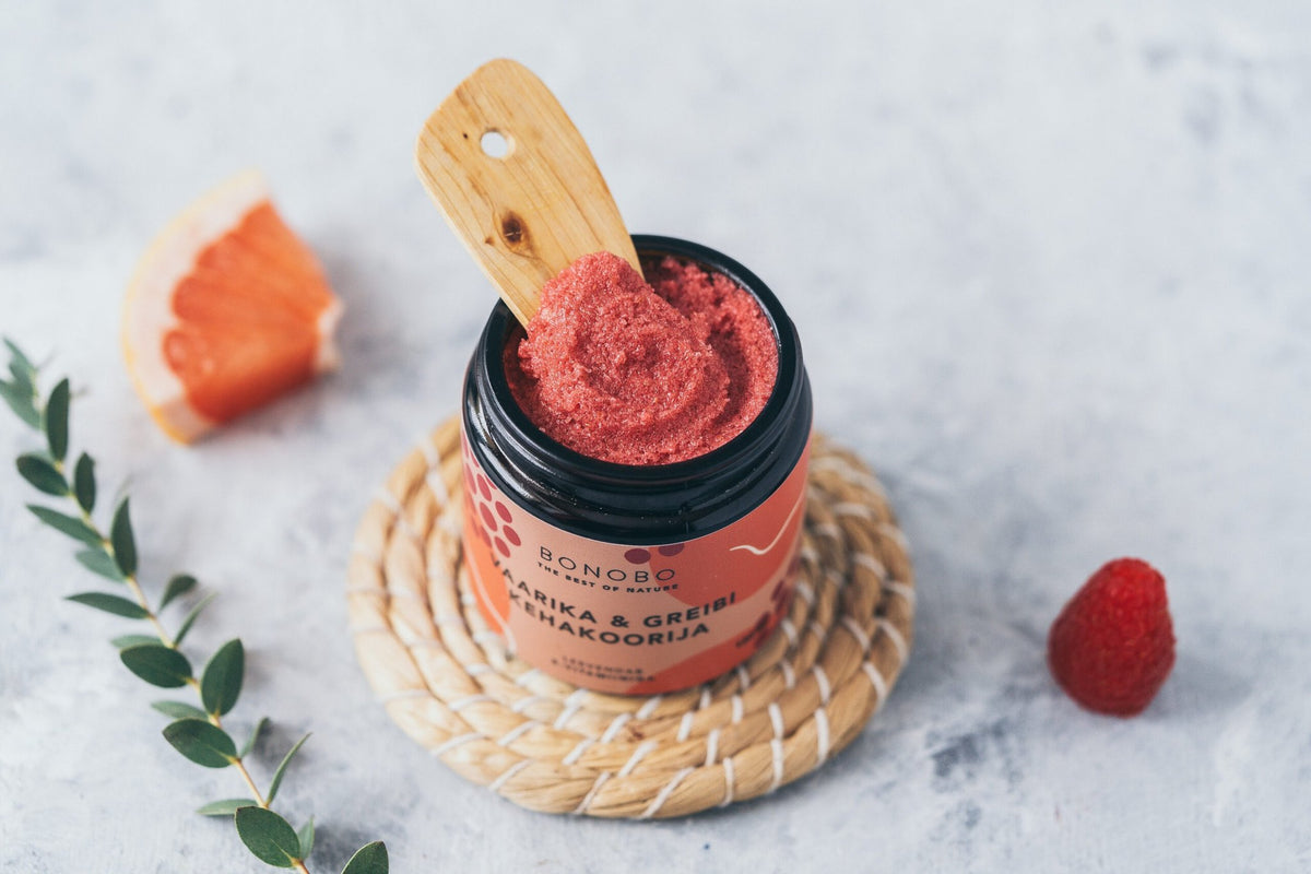 2. Open jar of BONOBO Raspberry and Grapefruit Body Scrub with wooden spatula, highlighting rich texture and natural ingredients