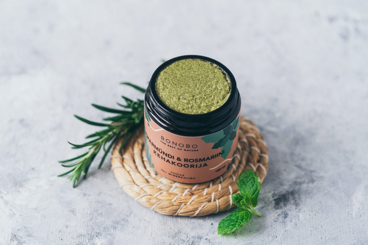 1. BONOBO peppermint and rosemary body scrub in jar with natural ingredients, shown with rosemary and mint leaves