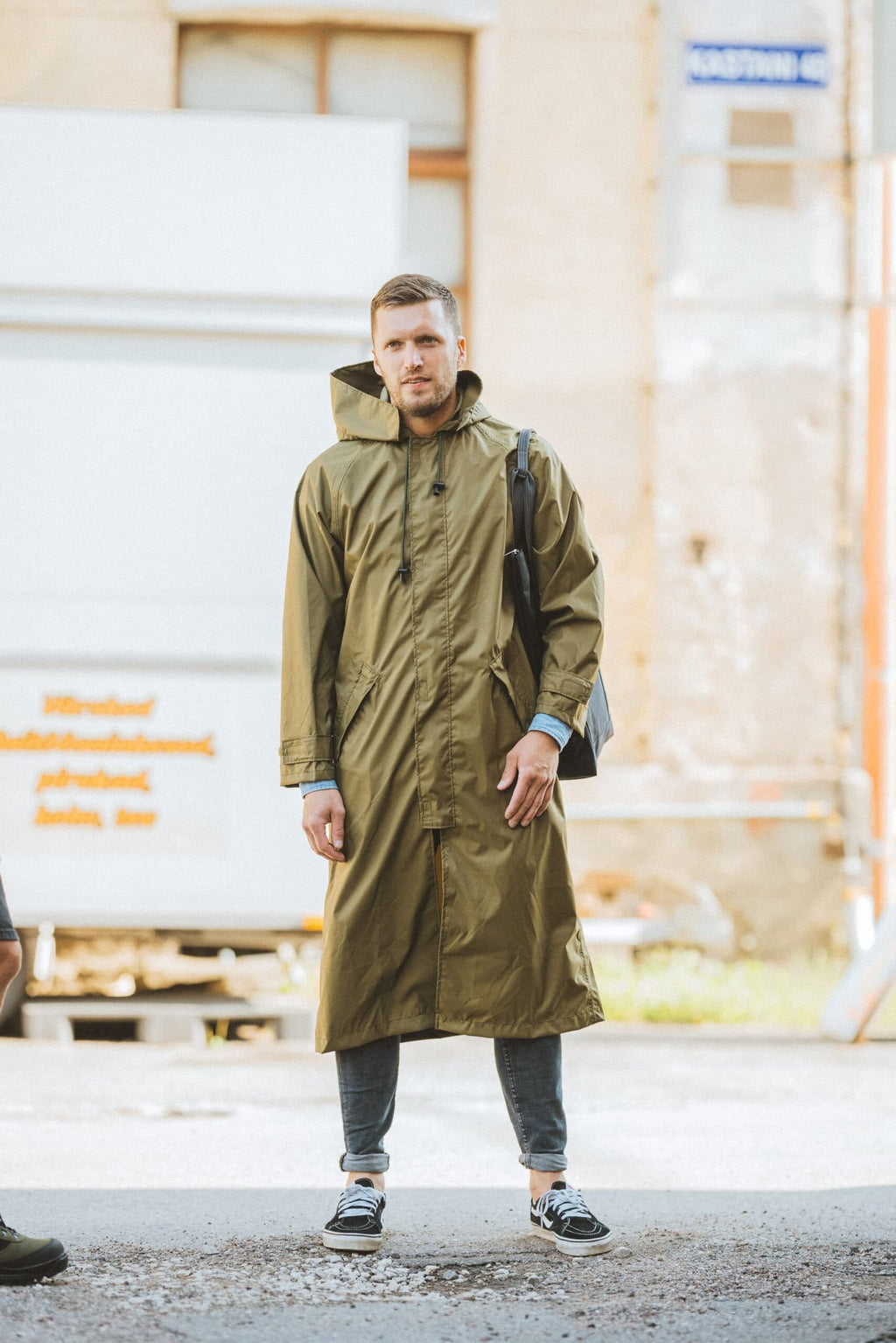 1. Men's Galvi Linda waterproof rain jacket in olive green, worn by model outdoors, showcasing full-length design and adjustable hood