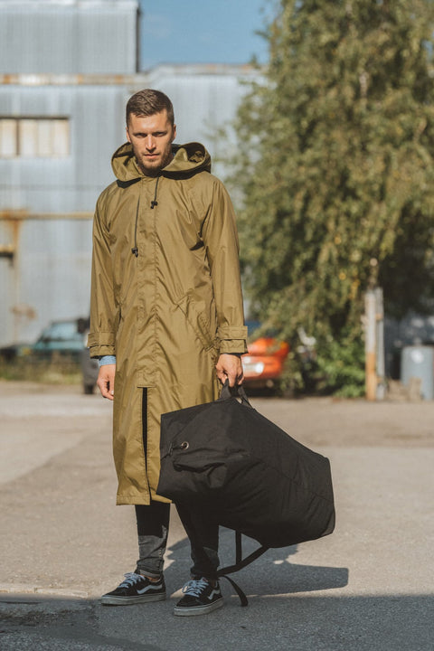 3. Men's Galvi Linda waterproof rain jacket in olive green, shown with matching black storage bag, highlighting outdoor setting