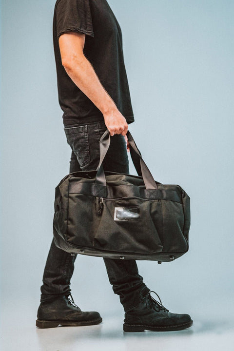 1. Galvi-Linda Travel Bag 008 in black carried by male model, showcasing durable Cordura material and sturdy handles