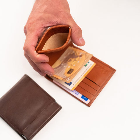 2. Close-up of Papillon Wallet No. 35 in cognac leather, showing coin pocket and card slots with hand holding it