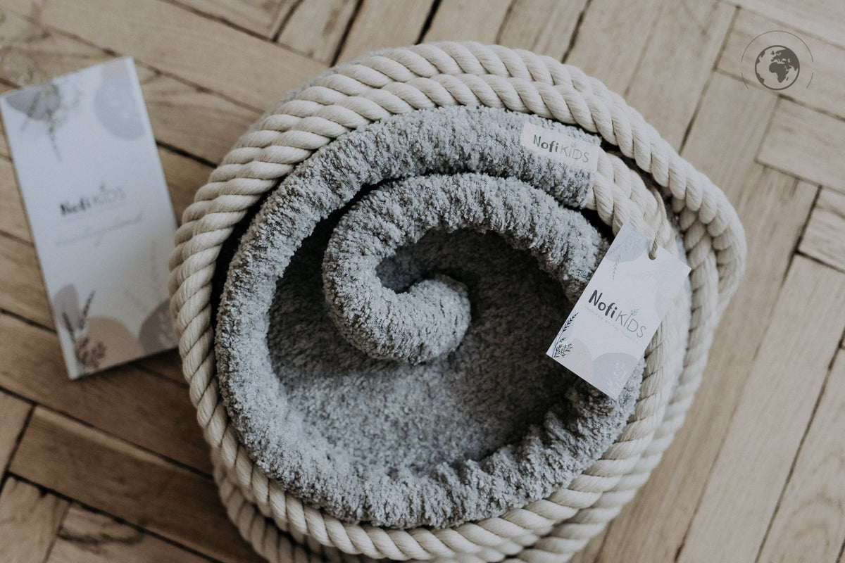 3. Close-up of Nofi KIDS HopOn Swing in bouclé stone grey fabric with cotton rope, showing brand tag on wooden floor