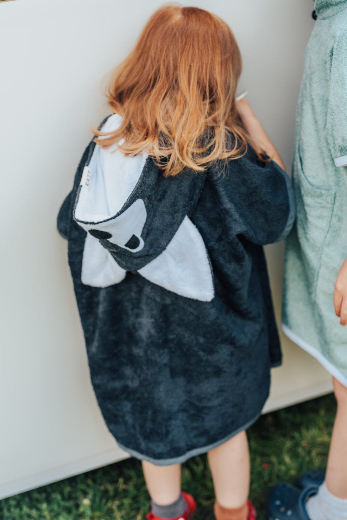 4. Close-up of RÄTT Short-Sleeve Poncho WOLF on child, emphasizing bamboo terry fabric