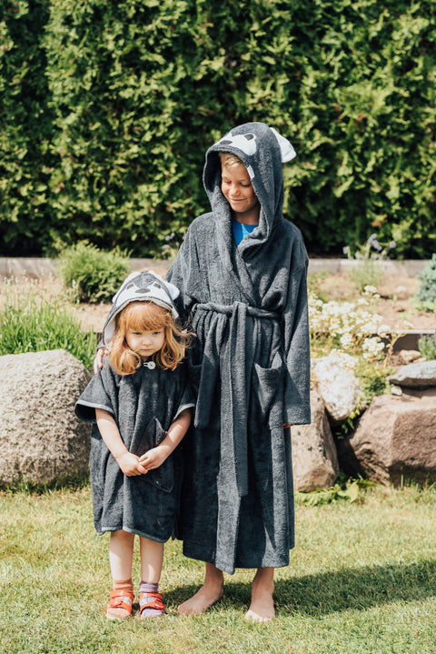 1. Two children wearing RÄTT WOLF Bamboo Terry Bathrobe for kids, featuring cozy hoods and belts, in a garden setting