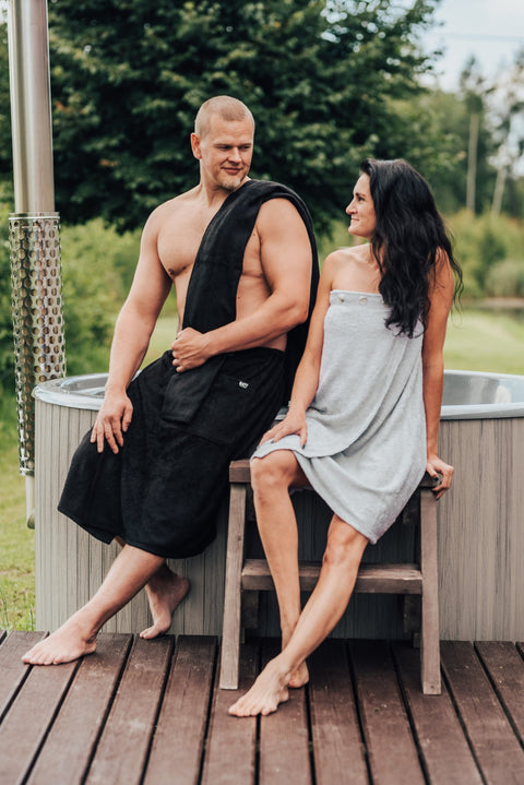 3. Men's dark grey bamboo terry spa wrap by RÄTT, shown with male model sitting by a hot tub