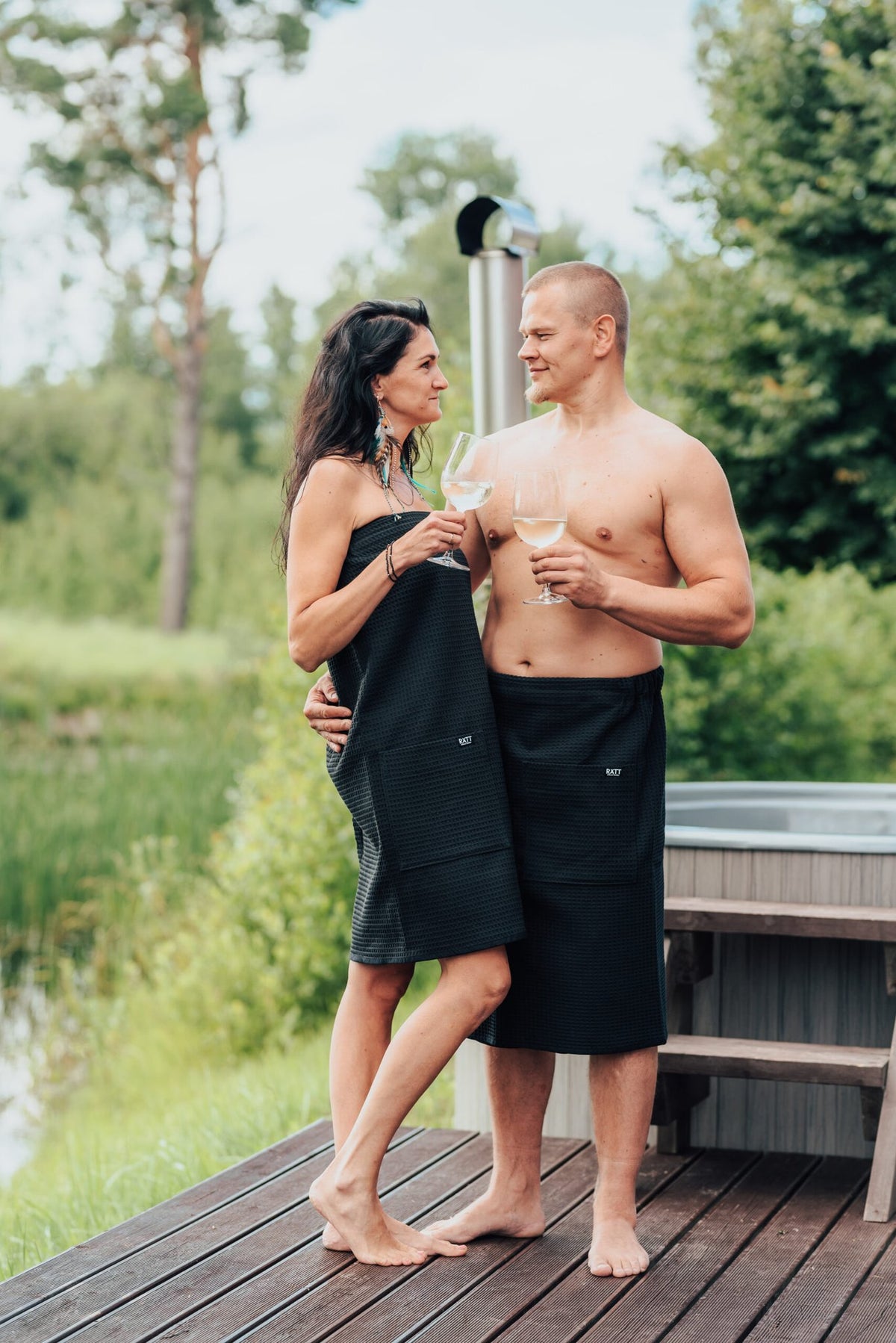 1. Men's black cotton waffle spa wrap by RÄTT, worn by male and female models outdoors, ideal for spa or sauna