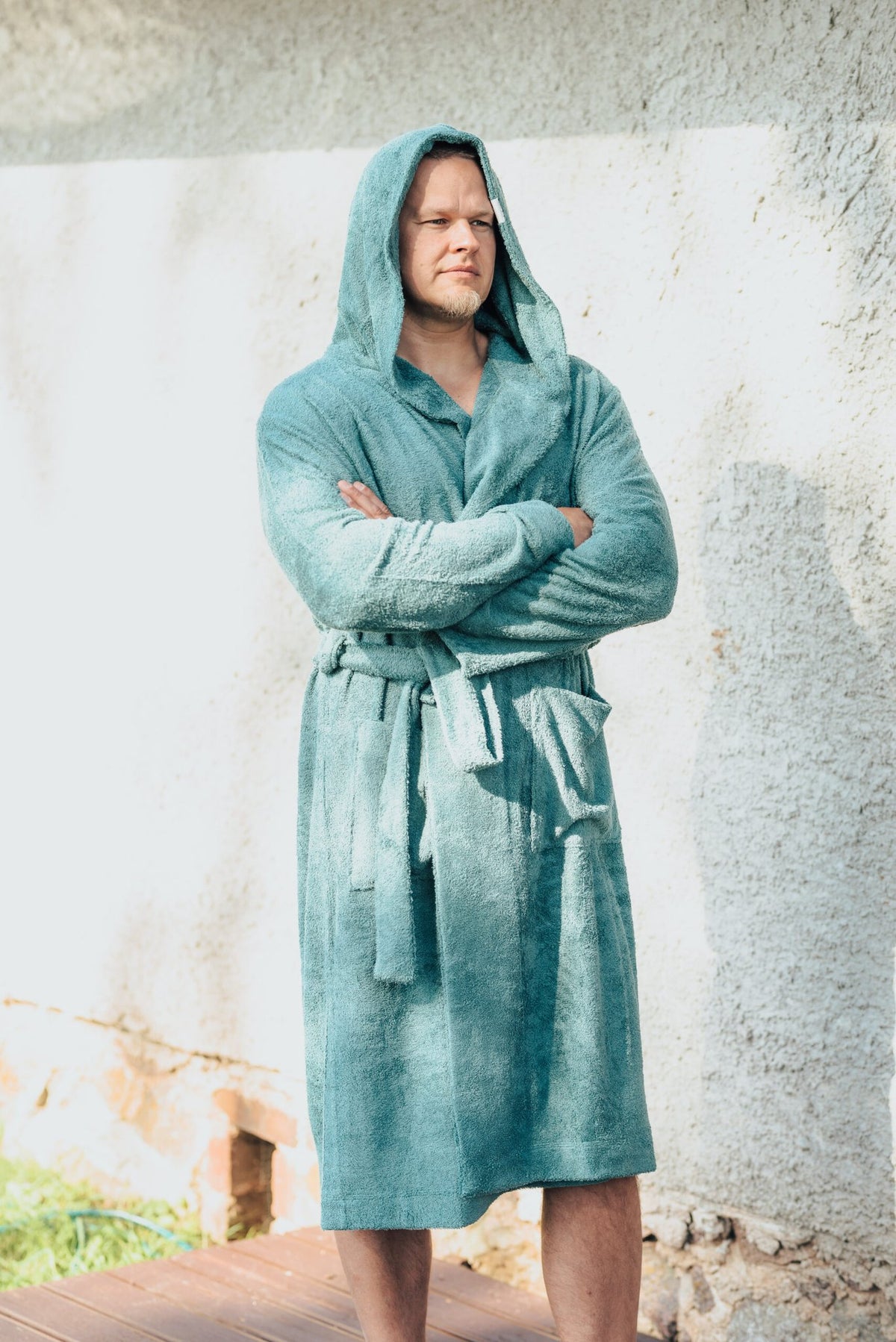 4. Men's teal bamboo terry bathrobe with hood, worn outdoors, highlighting belt closure and pockets