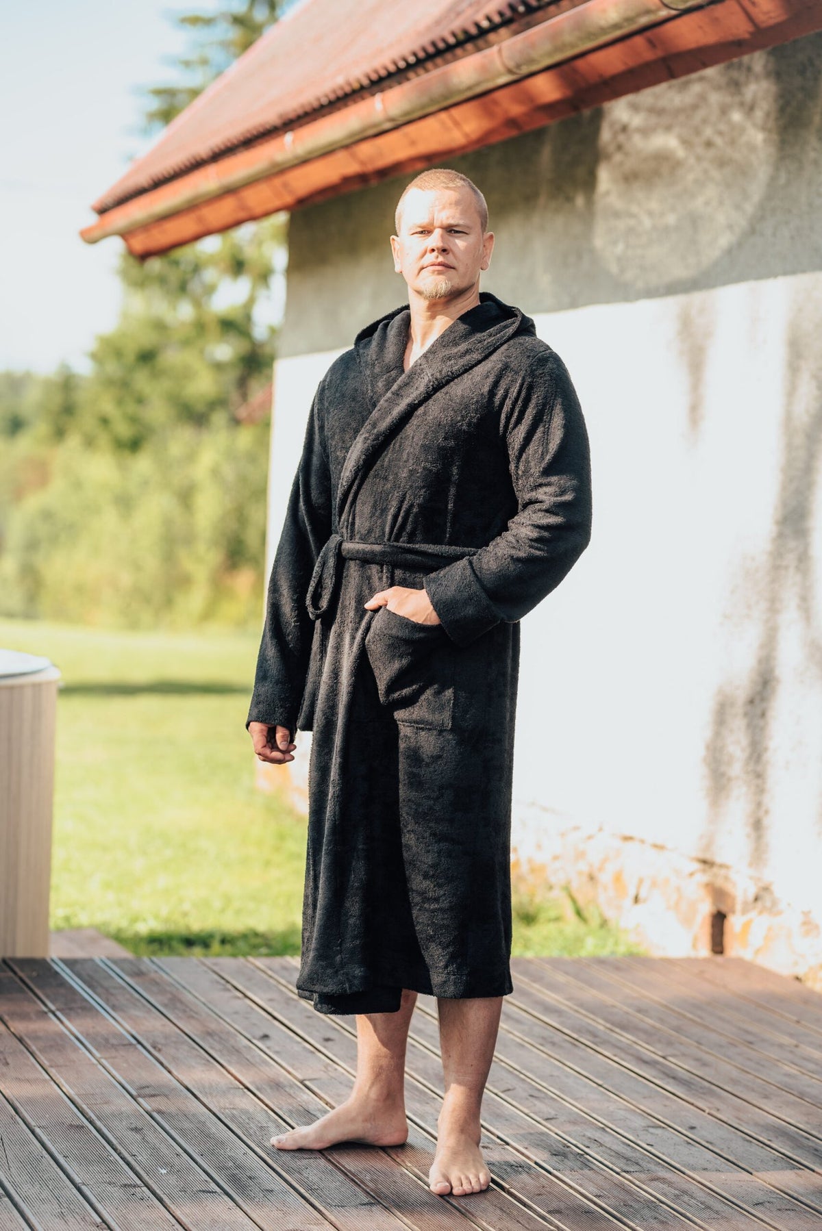 5. Men's black bamboo terry bathrobe with hood, shown outdoors, featuring belt closure and pockets
