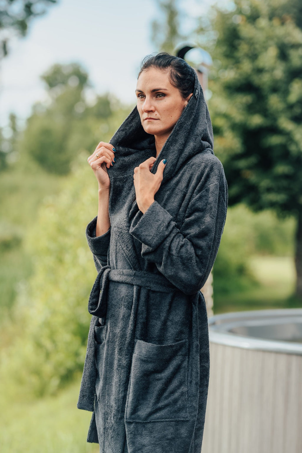 3. Women's black bamboo terry bathrobe with hood, shown outdoors with hands holding the hood
