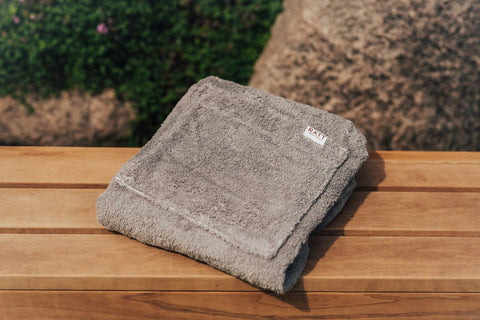 5. Close-up of folded gray RÄTT spa wrap on wooden surface, showing cotton terry texture