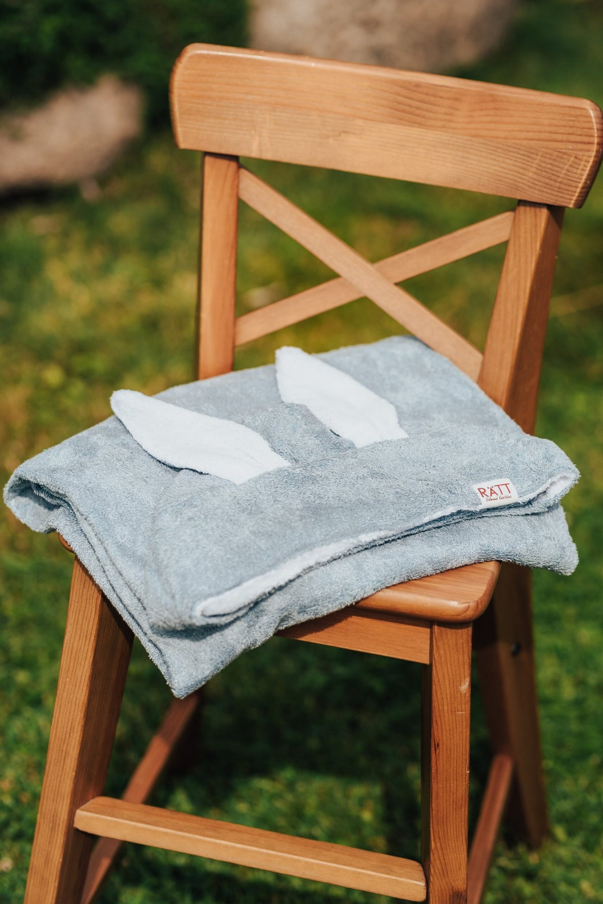 8. Blue RÄTT Hooded Baby Bath Towel TEDDY with teddy ears on wooden chair, outdoor setting