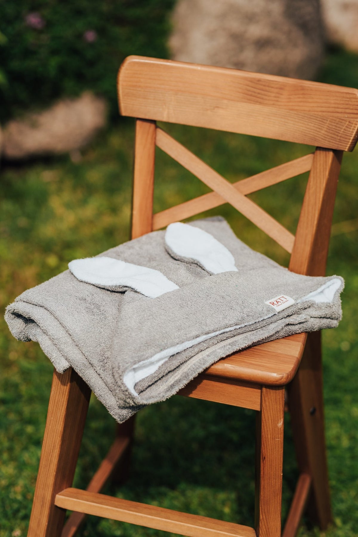 7. Gray RÄTT Hooded Baby Bath Towel TEDDY with teddy ears on wooden chair, outdoor setting