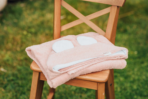 5. Pink RÄTT hooded baby bath towel with rabbit ears, folded on wooden chair