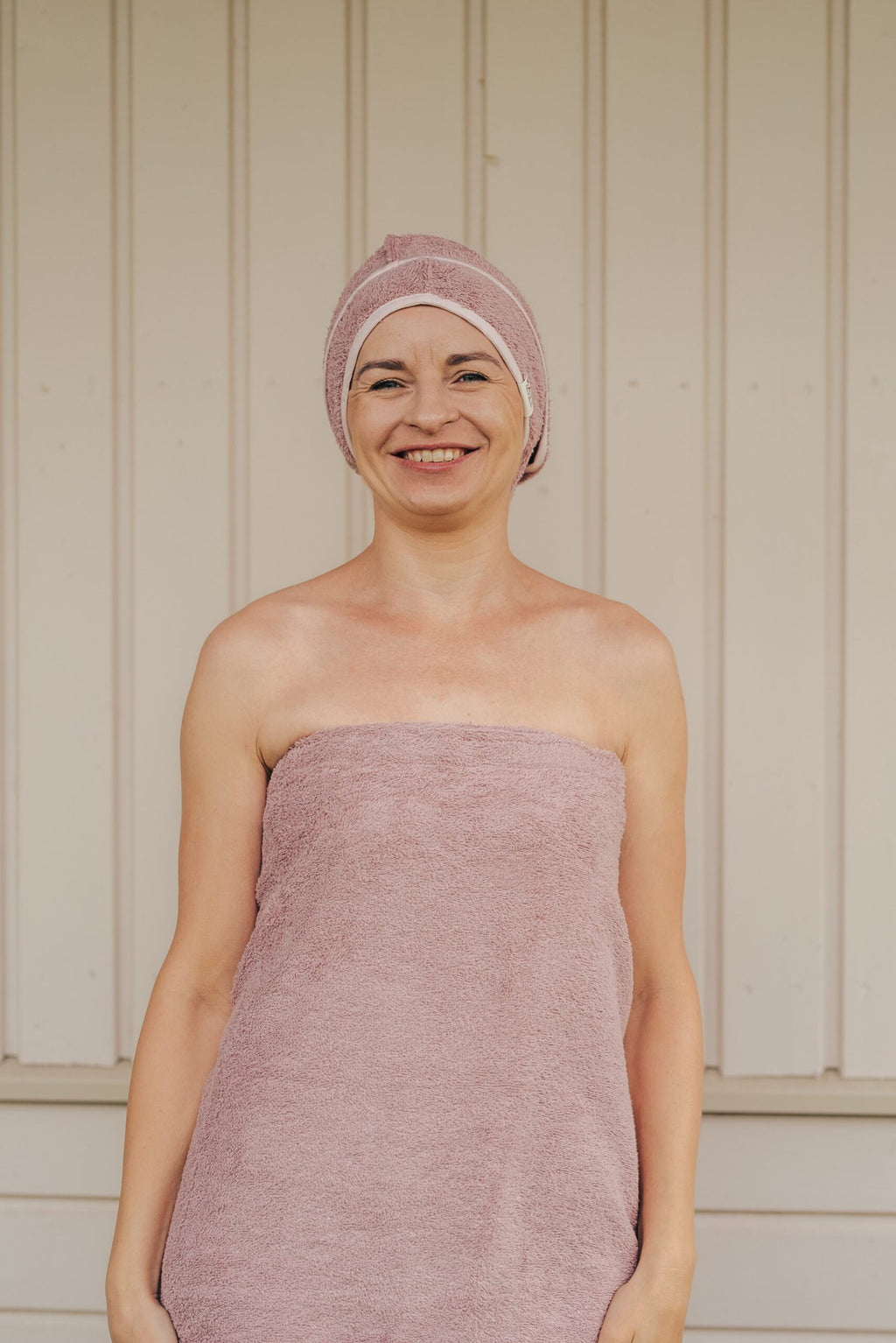 3. Smiling woman wearing RÄTT bamboo terry hair wrap in pink, highlighting soft and absorbent material