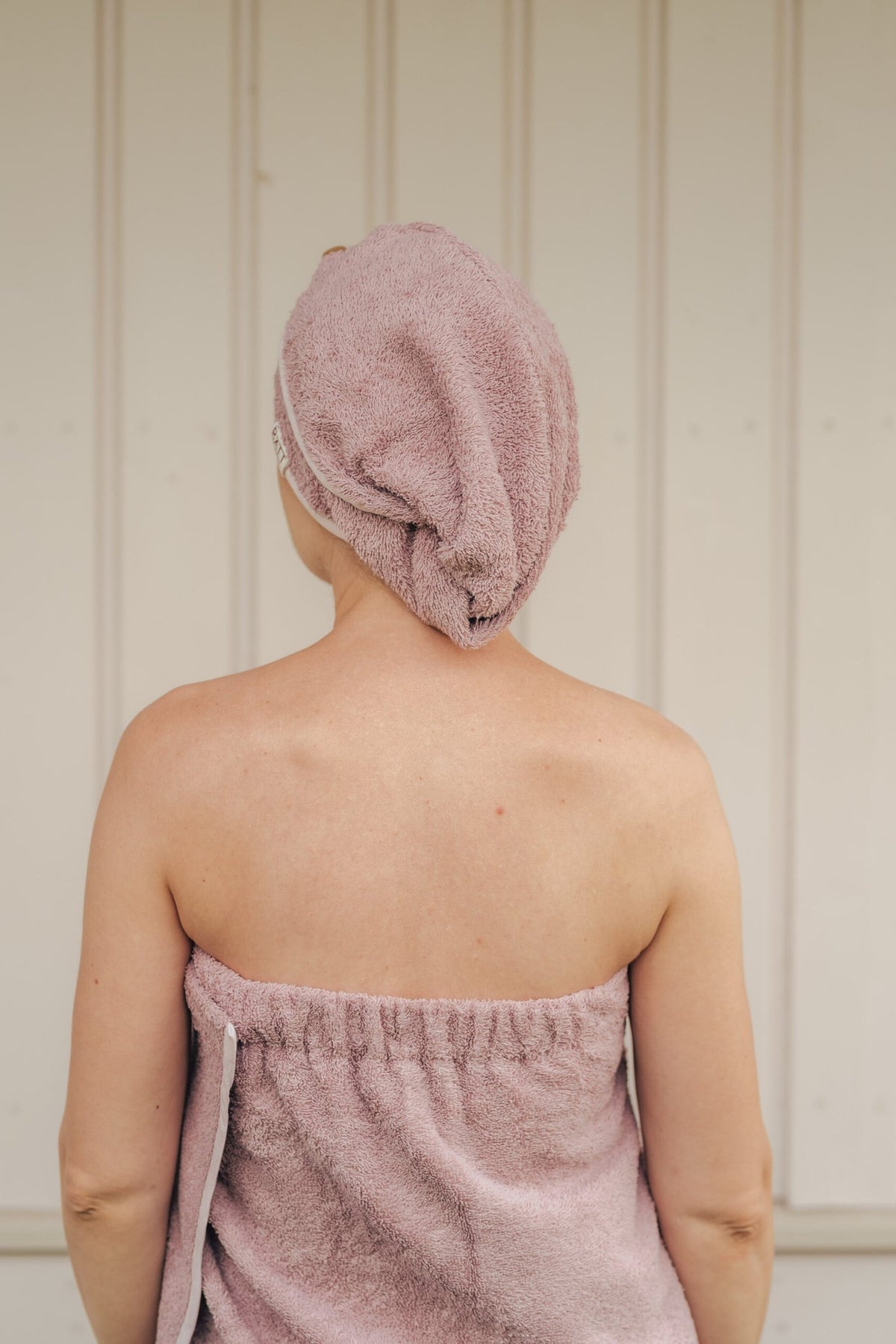 2. Woman wearing RÄTT bamboo terry hair wrap in pink, shown from the back, highlighting secure fit