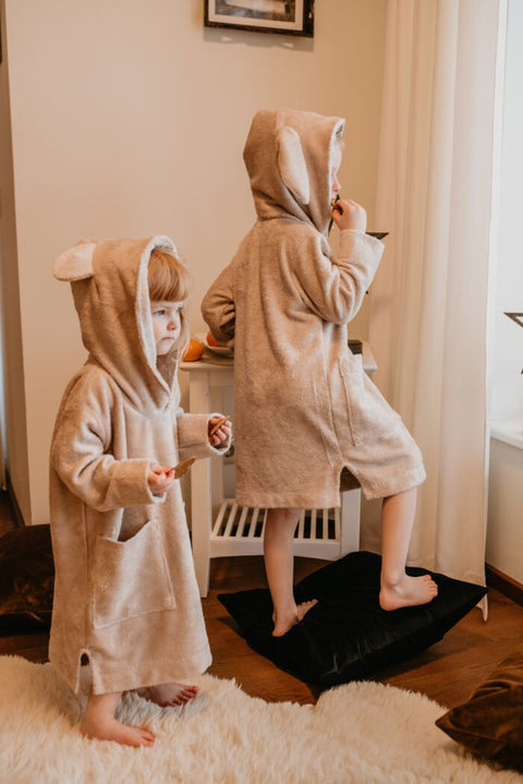 2. Two toddlers in beige RÄTT long-sleeve poncho TEDDY, standing and playing in a room with star decorations