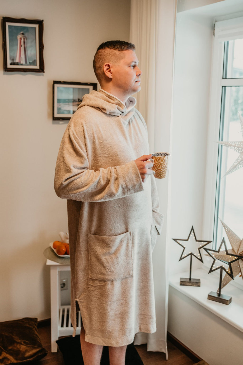 4. Men's beige bamboo terry long-sleeve poncho with hood, worn by model holding a mug indoors
