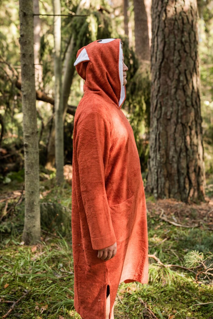 1. Women's short-sleeve poncho FOX in bamboo terry, shown in side view with hood, in a forest setting