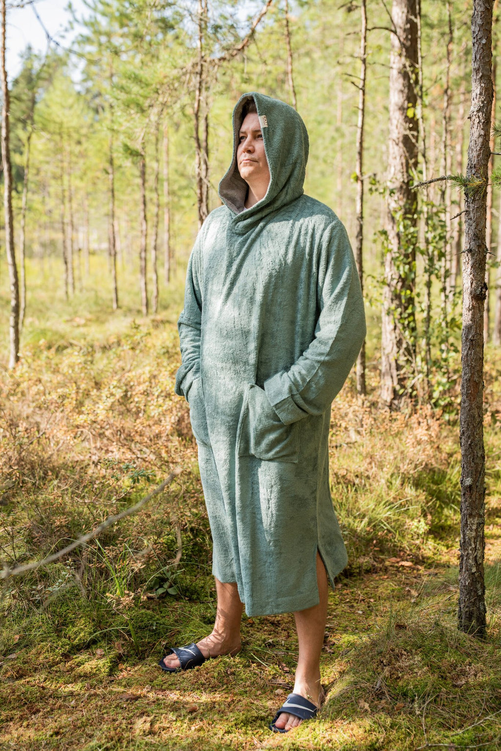 6. Men's green bamboo terry long-sleeve poncho with hood, worn by model standing in a forest