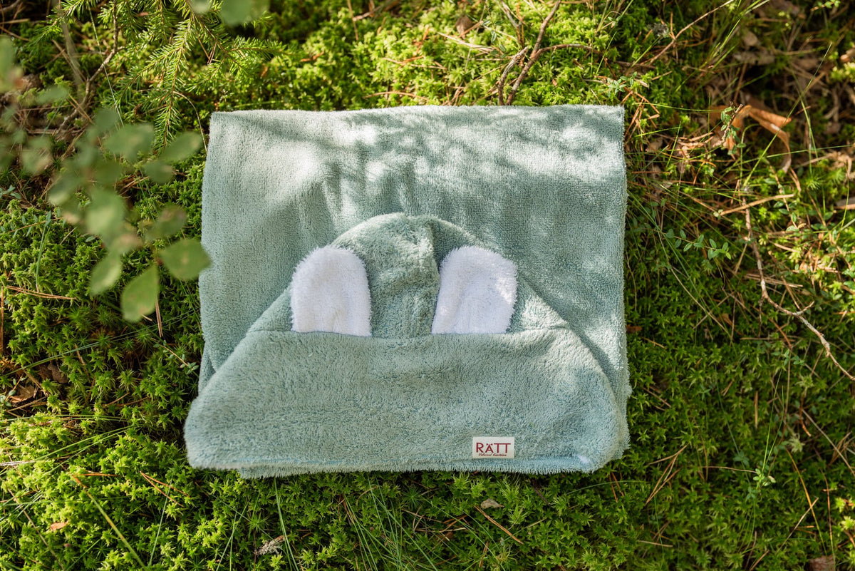 3. RÄTT hooded baby bath towel with rabbit ears in green, displayed on grass