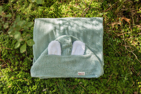 3. RÄTT hooded baby bath towel with rabbit ears in green, displayed on grass