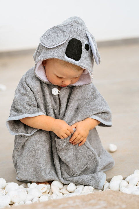 5. Toddler in grey RÄTT short-sleeve poncho with koala hood, sitting among white stones
