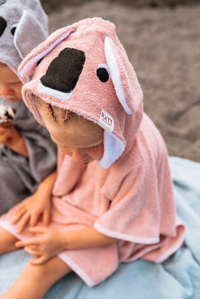 6. Close-up of toddler in pink RÄTT short-sleeve poncho with koala hood, showing brand tag